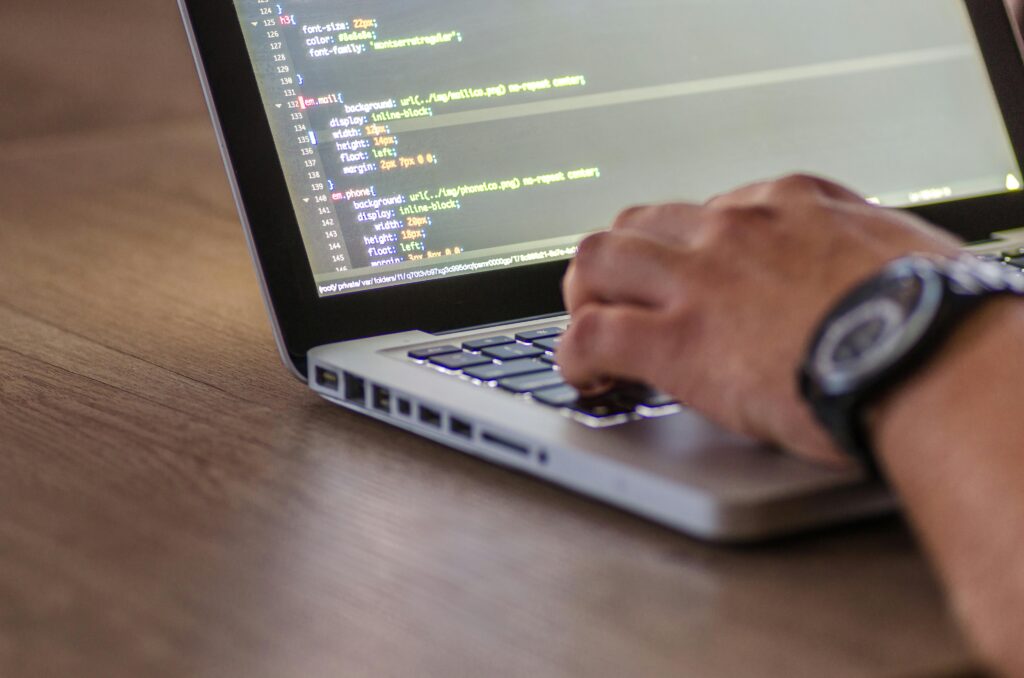  on a laptop at home, sorrounded by tech gadgets, symbilizing the growth of remote tech jobs and the digital workforce trend